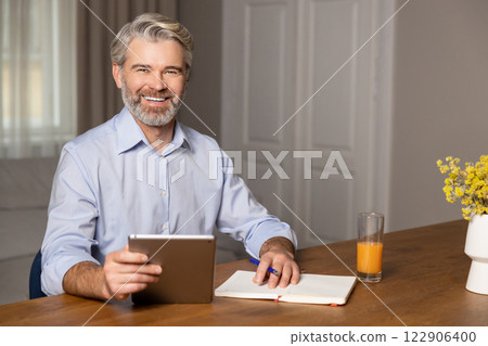 Gray-haired caucasian bearded man sitting at the laptop and working Gray-haired caucasian bearded man sitting at the laptop and working 122906400