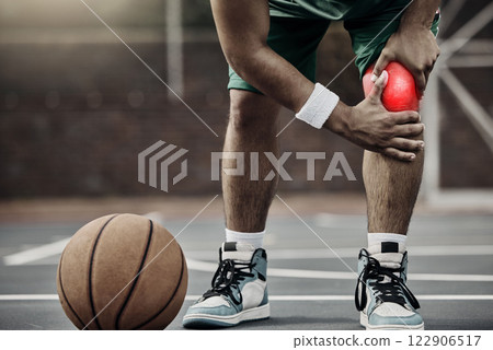 Sports, injury in basketball and knee pain or athlete man while on an outdoors court holding his hurt leg during training or exercise for hobby. Closeup of male hands on glowing red body part 122906517