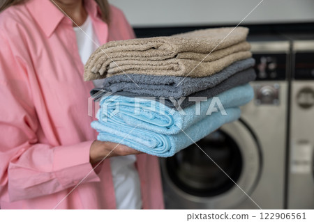 Contented mature caucasian woman holding a pile of clean clothes 122906561