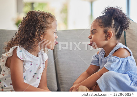 Funny, crazy and silly kids enjoy playing and having fun together in home living room sofa. Latino children or sisters stick out tongue and enjoy childhood on cozy, couch and comfortable family home 122906824