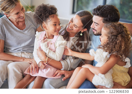 Love, relax and happy family introduction on sofa, laughing and playing in a living room together. Parents, kids and grandmother talking and enjoying quality time with sweet interracial children 122906830