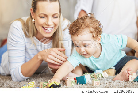 Mother, kid and play learning block toys on floor for educational bonding time together in family home. Young, caring and loving woman helping toddler with child development and coordination skills. Mother, kid and play learning block toys on floor for educational bonding time together in family home. Young, caring and loving woman helping toddler with child development and coordination skills. 122906853