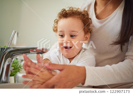 Mother, baby and bathroom cleaning their hands for health and hygiene in home. Child, water and mom teaching to wash dirt on palm and fingers to stop germs, bacteria and virus for kid bodycare 122907173