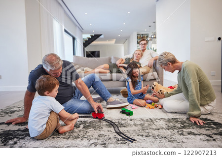 Family care, children love and grandparents happy with toys in living room with kids, smile train game and teddy bear in house. Mother and father relax on couch with elderly people and sibling games 122907213
