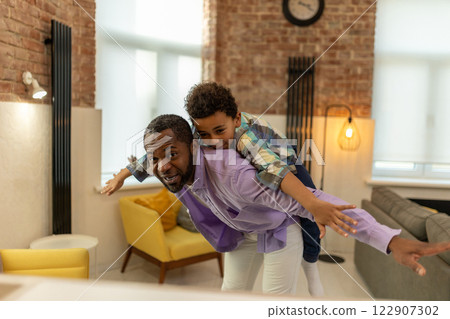 Dark-skinned man holding a boy on his back and both looking enjoyed 122907302