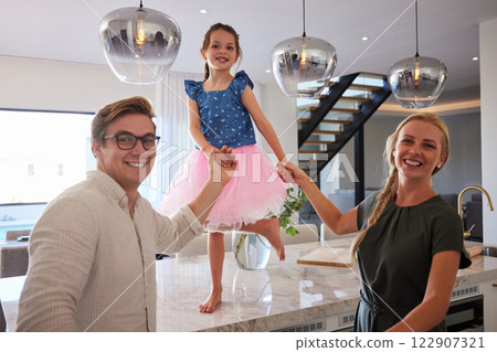 Girl, dance and table, parents, hands and smile bonding together in home kitchen. Happy, family and house, with mom, dad and child being silly, ballet and skirt dancing barefoot on marble countertop 122907321