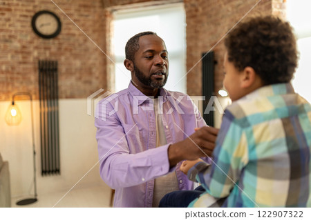 African american bearded man helping his son to get dressed 122907322