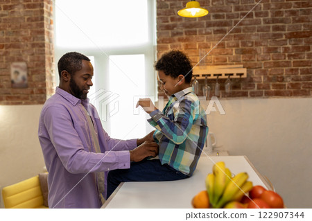 Father and son at home getting dressed in the kitchen and looking enjoyed 122907344
