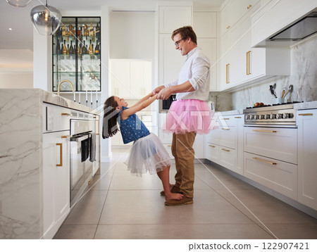 Love, father and child holding hands with feet balance game for fun in family home together. Care, love and support of young dad bonding with daughter in kitchen with ballet tutu costume. 122907421