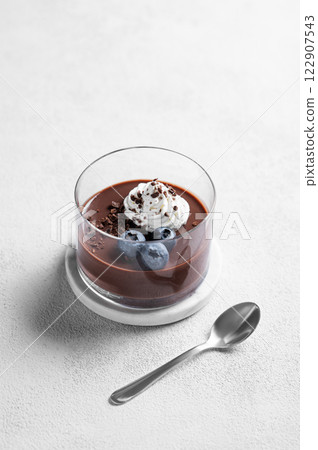 Chocolate pudding in a glass with whipped cream and fresh blueberry on a light background 122907543