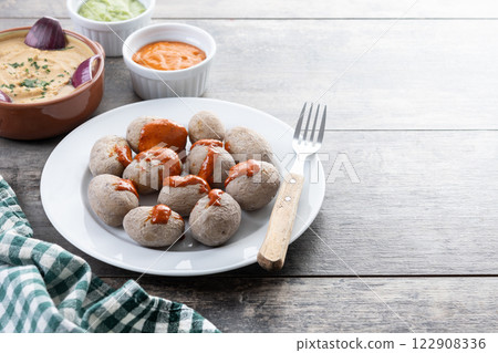Papas arrugadas with mojo and gofio escaldado on wooden table. Traditional Canary Islands food. Papas arrugadas with mojo and gofio escaldado on wooden table. Traditional Canary Islands food. 122908336