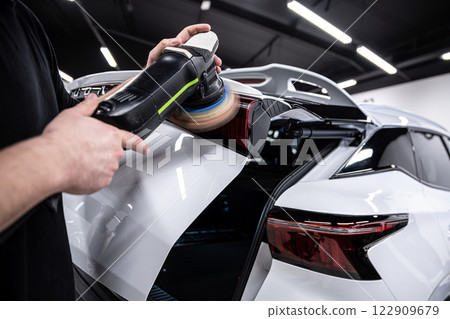 Detailing professional meticulously polishes a white cars paint and tail lamp Detailing professional meticulously polishes a white cars paint and tail lamp 122909679