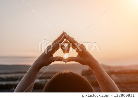 Hands Heart Sunset: Silhouette forming heart shape during sunset, symbolizing love, peace, hope. 122909931