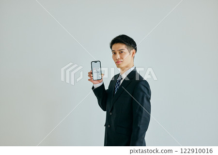 一名 20 多歲的年輕人拿著智慧型手機 新 NISA 和 iDeCo 122910016