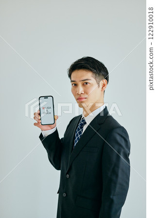 一名 20 多歲的年輕人拿著智慧型手機 新 NISA 和 iDeCo 122910018