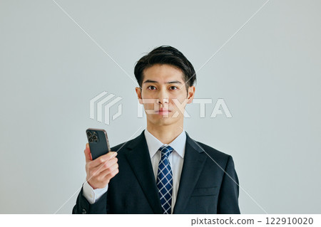 一名二十多歲的年輕人拿著智慧型手機 一名二十多歲的年輕人拿著智慧型手機 122910020