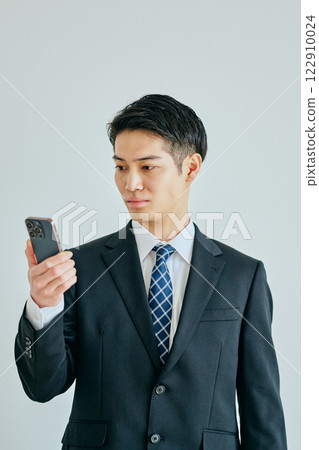 一名二十多歲的年輕人拿著智慧型手機 一名二十多歲的年輕人拿著智慧型手機 122910024