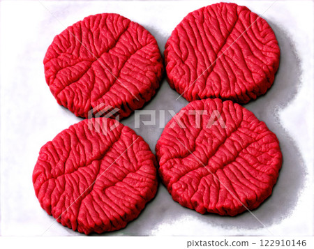 A close-up of raw ground beef patties being seasoned with salt and pepper. The beef is finely textured, slightly moist, A close-up of raw ground beef patties being seasoned with salt and pepper. The beef is finely textured, slightly moist, 122910146