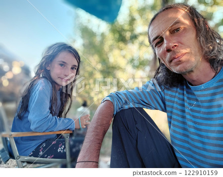 Father and daughter sitting outdoors sharing a bonding moment in nature Father and daughter sitting outdoors sharing a bonding moment in nature 122910159