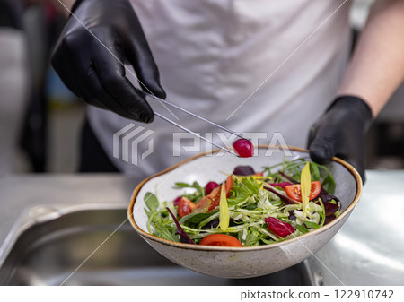 Chef using tongs to add pickled onion Chef using tongs to add pickled onion 122910742