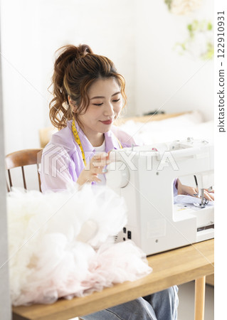 Cute woman using a sewing machine Cute woman using a sewing machine 122910931