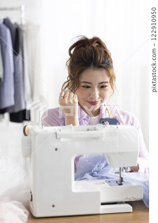Cute woman using a sewing machine 122910950