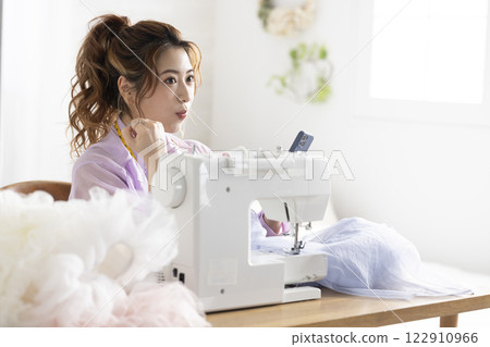 Cute woman using a sewing machine 122910966