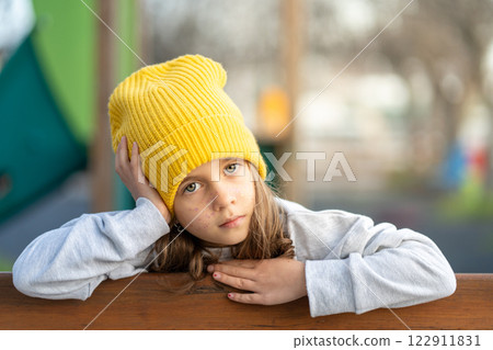 Serious girl in yellow cap with freckles touching Serious girl in yellow cap with freckles touching 122911831
