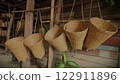 A handmade container made from woven bamboo, hung on the wall. 122911896
