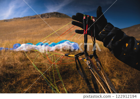 Paraglider untangles the lines of a kite before takeoff on a sunny day. Checking the sports equipment after landing on the ground 122912194