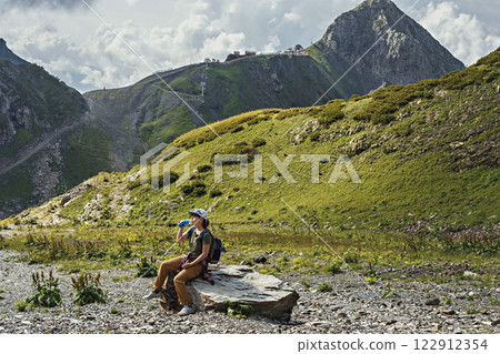 young woman with backpack sitting on rock in scenic mountain landscape, drinking water from bottle while resting during hike Outdoor adventure and travel concept , recreation and trekking Copy space young woman with backpack sitting on rock in scenic mountain landscape, drinking water from bottle while resting during hike Outdoor adventure and travel concept , recreation and trekking Copy space 122912354