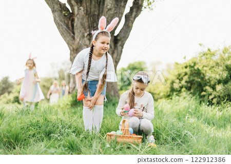 Easter egg hunt. Group Of Children Wearing Bunny Ears Running To Pick Up colorful Egg On Easter Egg Hunt In Garden. Easter tradition 122912386