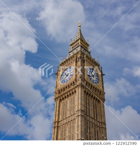A close up shot of the iconic Big Ben clock tower in London, showing intricate architectural details against a bright blue sky. 122912590