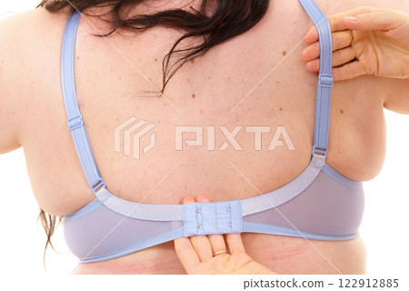 Bra fitter help plus size woman find perfect fit. Back view. Bra fitter help plus size woman find perfect fit. Back view. 122912885