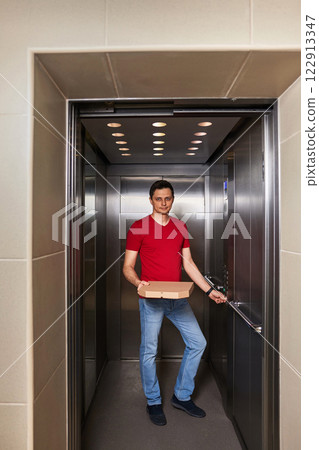 Deliveryman holding pizza box in elevator, food delivery to your home. Deliveryman holding pizza box in elevator, food delivery to your home. 122913347
