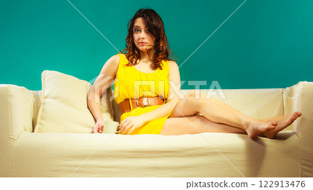 woman sitting on sofa holds coffee cup woman sitting on sofa holds coffee cup 122913476