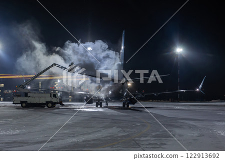 Ground deicing of a passenger jetliner on the night airport at winter 122913692