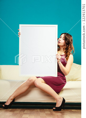 woman on sofa holding blank presentation board. woman on sofa holding blank presentation board. 122913701