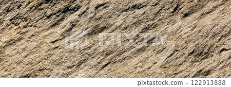 A close up of a rough, cracked rock surface with earthy brown and beige tones. The natural texture and weathered details make it ideal for backgrounds, geology themes, and organic material references. A close up of a rough, cracked rock surface with earthy brown and beige tones. The natural texture and weathered details make it ideal for backgrounds, geology themes, and organic material references. 122913888