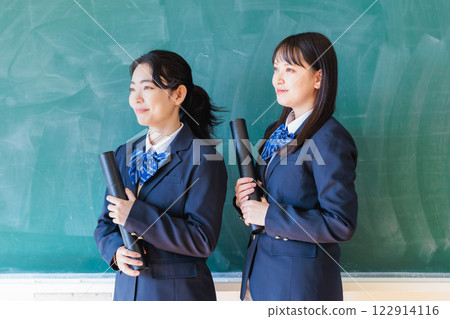 Female student holding a diploma in front of a blackboard 122914116