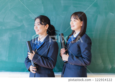 Female student holding a diploma in front of a blackboard Female student holding a diploma in front of a blackboard 122914122