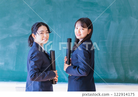 Female student holding a diploma in front of a blackboard 122914175
