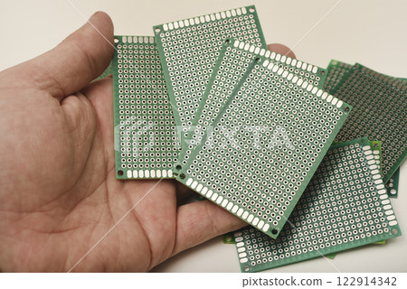 A green breadboard for electronics. The printed circuit board is in your hand. A green breadboard for electronics. The printed circuit board is in your hand. 122914342