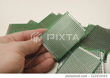 A green breadboard for electronics. The printed circuit board is in your hand. A green breadboard for electronics. The printed circuit board is in your hand. 122914343