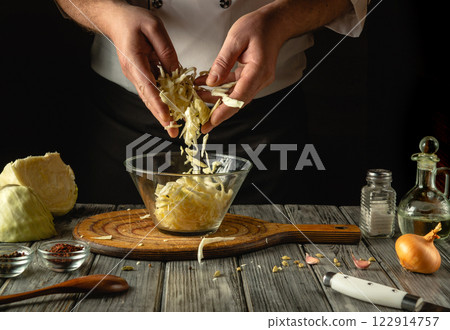 Hands skillfully stir crisp cabbage, aroma filling the air in the warmly lit kitchen. Ingredients and spices are artfully laid out on a wooden table, ready for a delicious meal. Hands skillfully stir crisp cabbage, aroma filling the air in the warmly lit kitchen. Ingredients and spices are artfully laid out on a wooden table, ready for a delicious meal. 122914757
