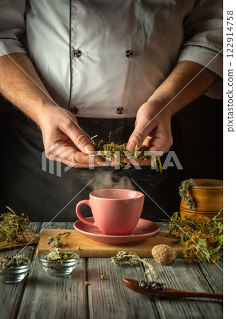 Experienced herbalist brews herbal tea. Hands holding dry medicinal chamomile to add to pink cup. Treatment of flu virus at home Experienced herbalist brews herbal tea. Hands holding dry medicinal chamomile to add to pink cup. Treatment of flu virus at home 122914758