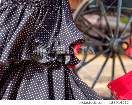 Traditional flamenco dress and carriage wheel at fair Traditional flamenco dress and carriage wheel at fair 122914912