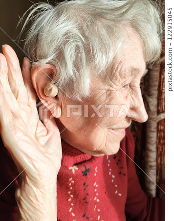 Middle age woman smiling confident using hearing aid at home 122915045