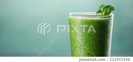 Refreshing green smoothie in a glass with mint garnish on a soft background. Refreshing green smoothie in a glass with mint garnish on a soft background. 122915548