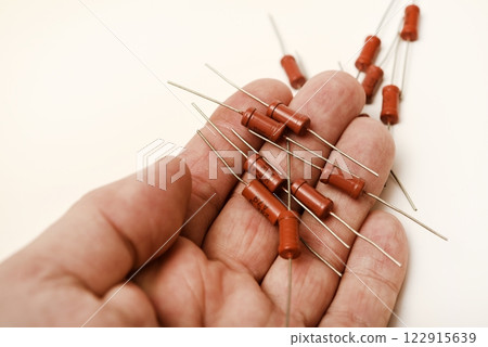 Old film resistors in your hand. Resistors with axial terminals. Elements of electronics. 122915639